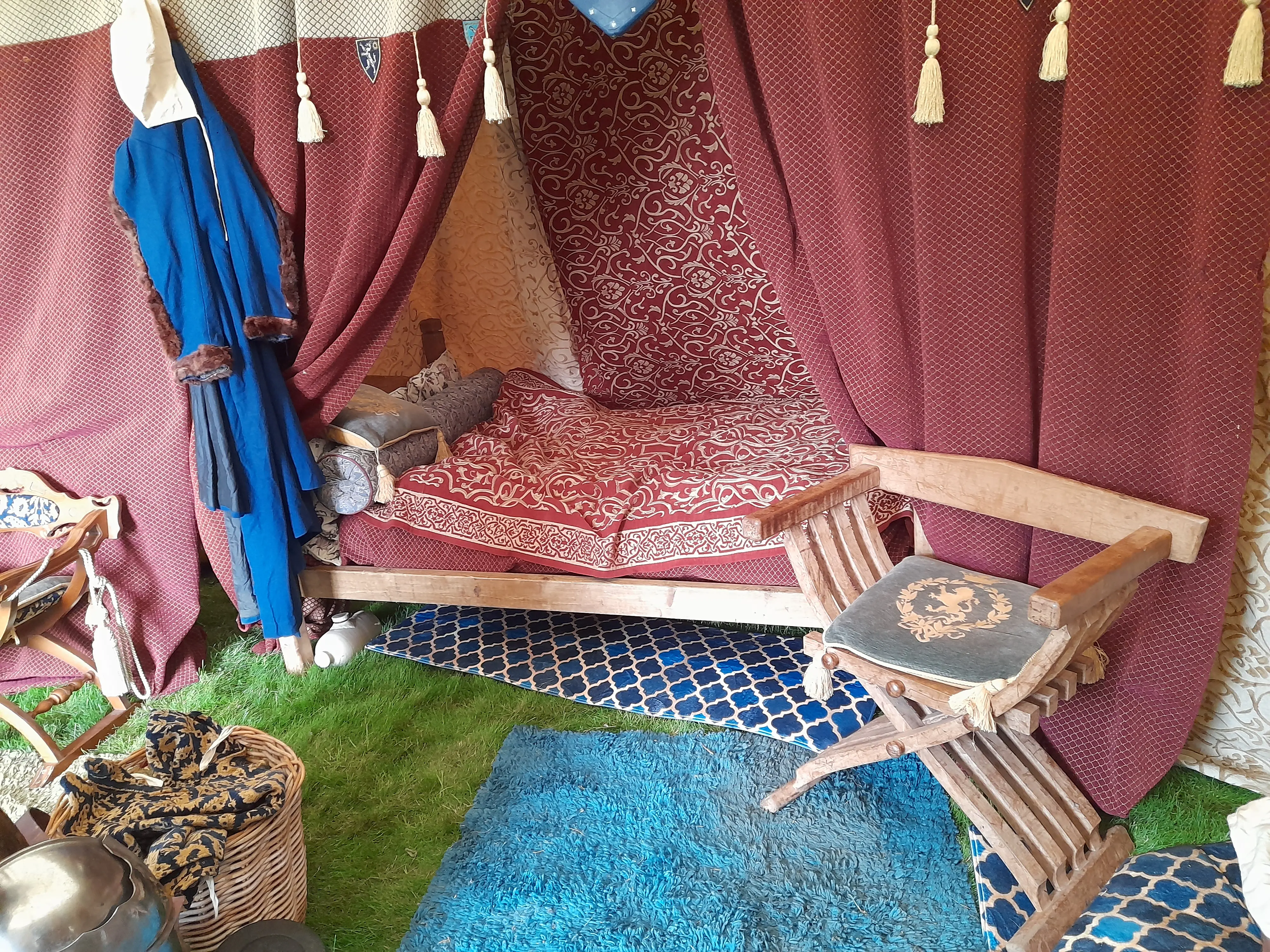 Inside a medieval tent with a four-poster bed surrounded by curtains and drapes