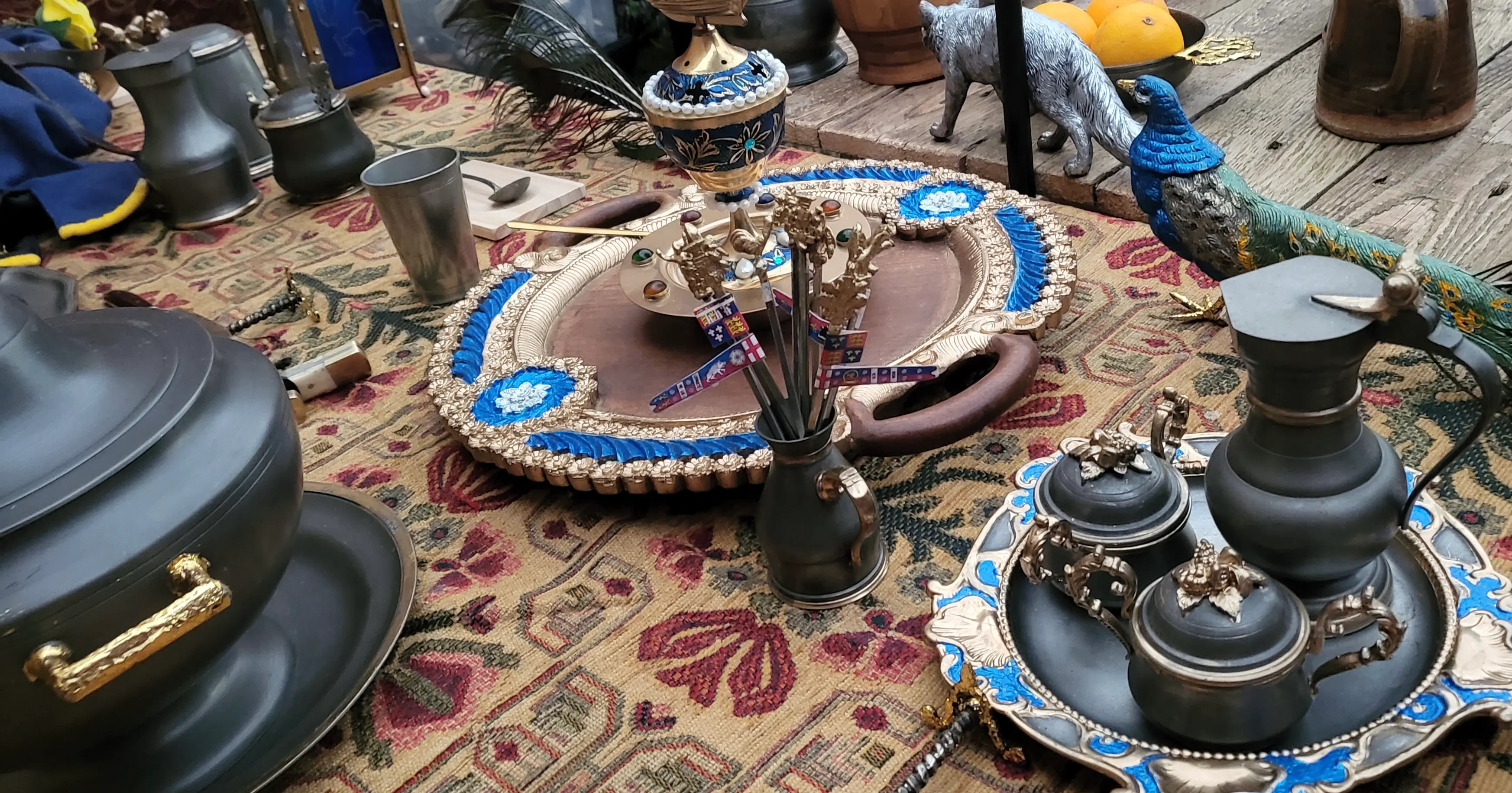 Close-up of ornate metal and wooden tableware displayed on a medieval feast table