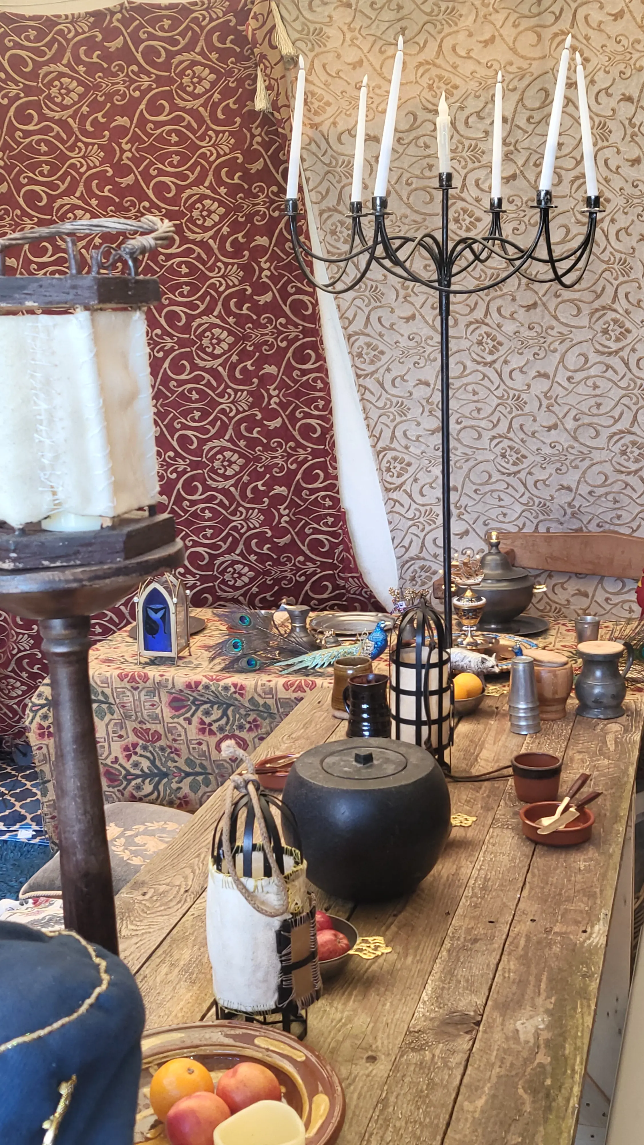 Cluttered wooden table with food, candles, implements, and a salt holder