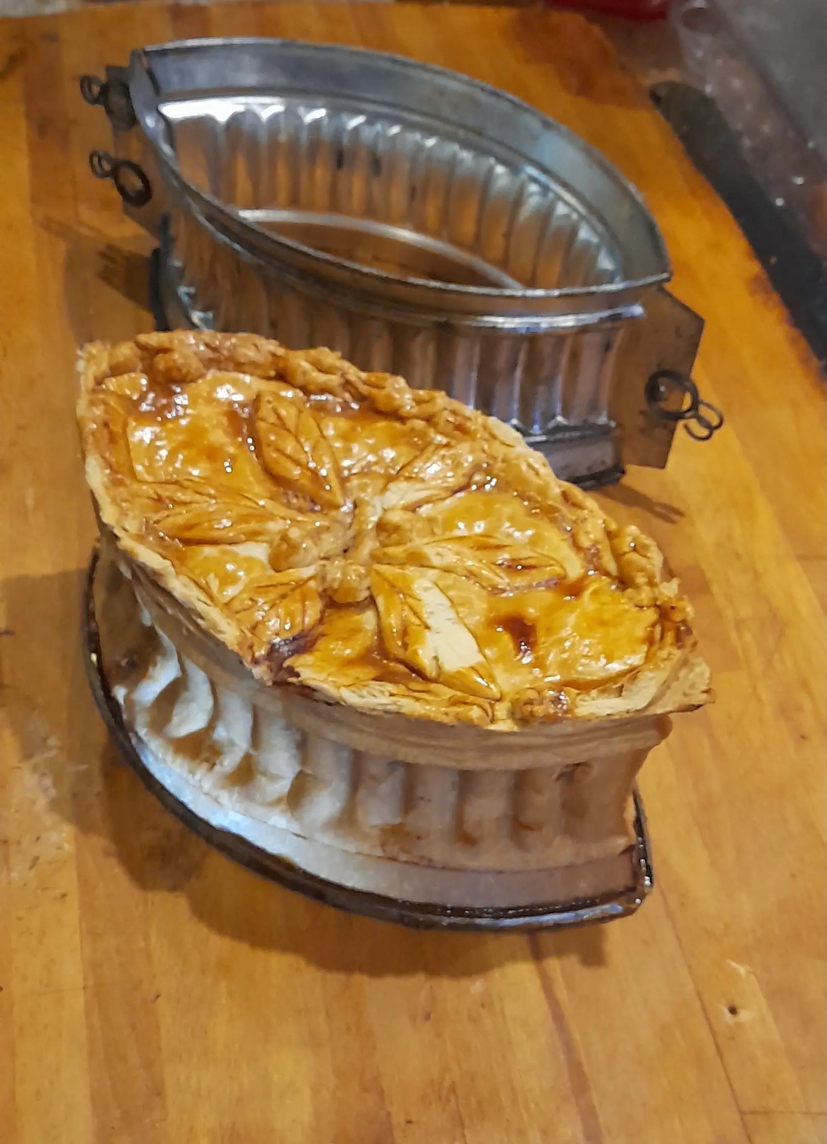 Close-up of a raised medieval pie next to the pastry case tin