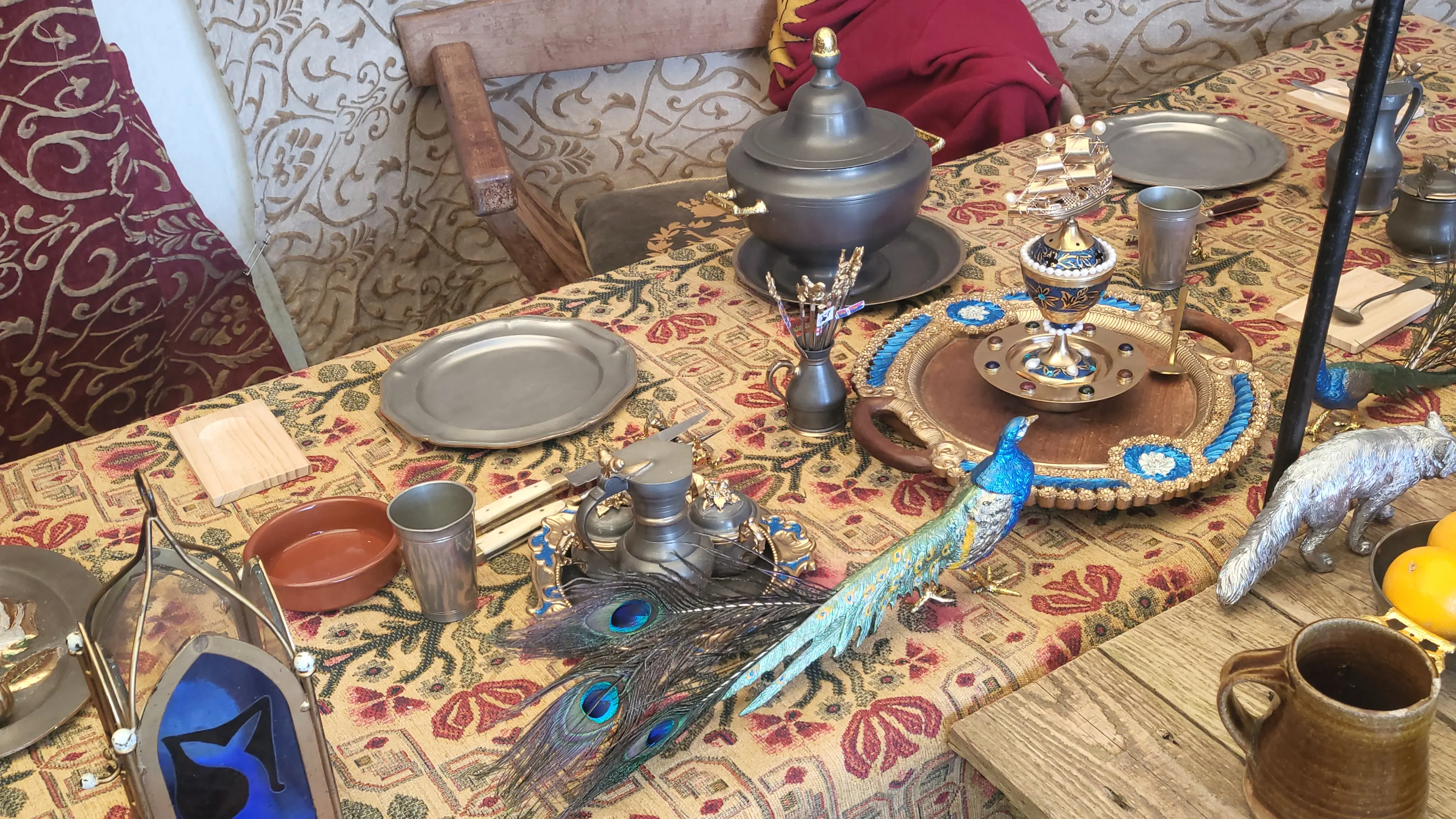 Medieval feast table with food, candles, and ornate metal and wooden tableware